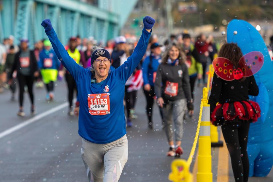 Half-marathon participant Susan Wright smiles as she puts her arms in the air at the Ambassador Bridge early in the morning during the 46th annual Detroit Free Press Marathon presented by MSU Federal Credit Union in Detroit on Sunday, Oct. 15, 2023.