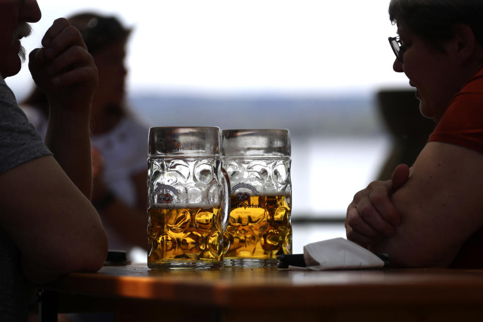 People enjoy the sunny weather and drink beer on the re-opening day of beer gardens, following the lifting of measures to avoid the spread of the corona virus, at lake 'Ammersee' in front of the alps in Inning, Germany, Monday, May 10, 2021. (AP Photo/Matthias Schrader)