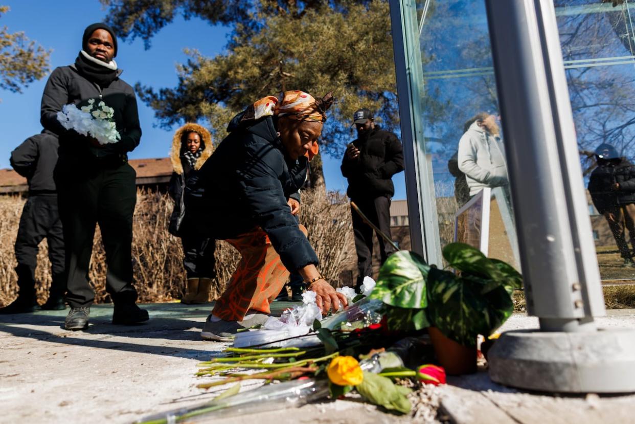 People place flowers at a vigil for Adu Boakye, a man who was fatally shot while waiting for the bus near a community centre in northwest on Feb. 24, 2024. Boakye was a 39-year-old man from Ghana who police said came to Toronto last November to support his family.  (Cole Burston/The Canadian Press - image credit)