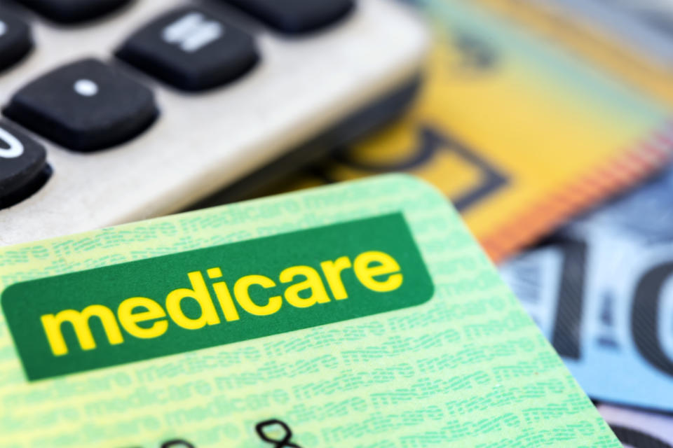 Australian Medicare card with calculator and cash background.