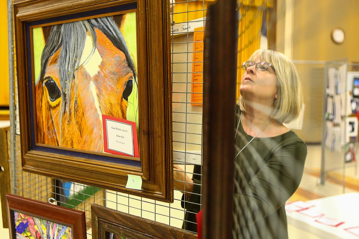 Penny Renfroe hangs a painting during set up for the Shauney P. Lucas Memorial Art Show in Whitesboro in 2016.