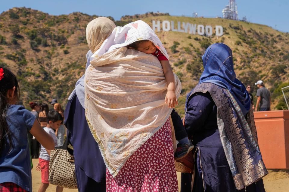 Tourists protect a sleeping child from the sun as they visit the Hollywood sign landmark in Los Angeles July 12, 2023.