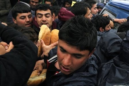 Refugees struggle for loaves of bread during food distribution by volunteers at a makeshift camp at the Greek-Macedonian border, near the village of Idomeni, Greece March 15, 2016. REUTERS/Alexandros Avramidis