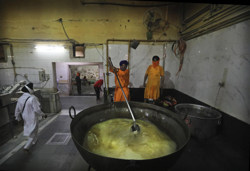 A Sikh cook stirs rice in a giant vessel in the kitchen hall of the Bangla Sahib Gurdwara in New Delhi, India, Sunday, May 10, 2020. The Bangla Sahib Gurdwara has remained open through wars and plagues, serving thousands of people simple vegetarian food. During India's ongoing coronavirus lockdown about four dozen men have kept the temple's kitchen open, cooking up to 100,000 meals a day that the New Delhi government distributes at shelters and drop-off points throughout the city. (AP Photo/Manish Swarup)