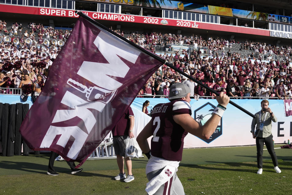 Mississippi State quarterback Will Rogers runs with a "Mike" flag in honor of former coach Mike Leach at the end of the ReliaQuest Bowl NCAA college football game Monday, Jan. 2, 2023, in Tampa, Fla. Mississippi State defeated Illinois. Leach died on Dec. 13, 2022, from a heart condition. (AP Photo/Chris O'Meara)