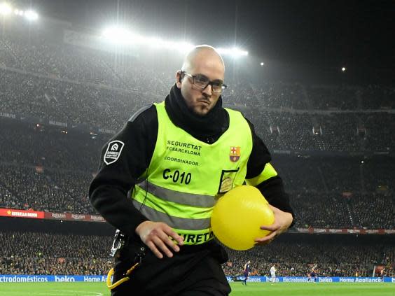 A steward helps to clear the pitch during a protest at El Clasico (Getty)