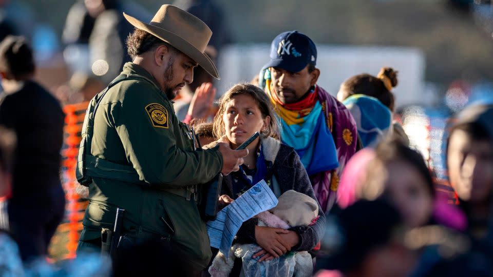 A US Border Patrol agent speaks with immigrants at a transit center near the US-Mexico border last week in Eagle Pass, Texas. Most had crossed the Rio Grande from Mexico the night before. - John Moore/Getty Images