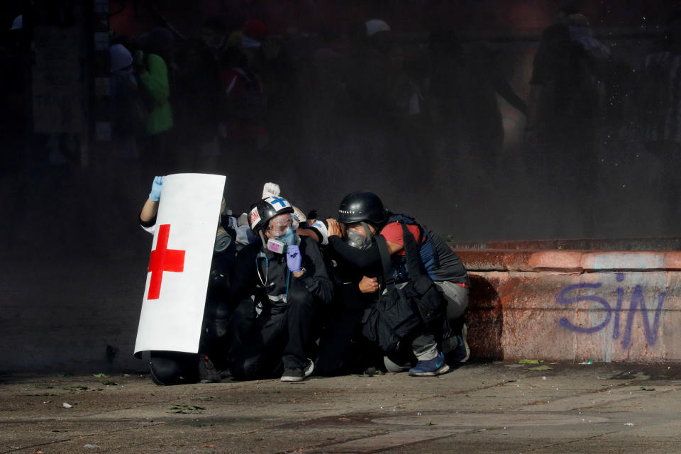 Members of a first aid team and a photographer take cover during an anti-government protest in Santiago, Chile on Oct. 28, 2019. (Photo: Henry Romero/Reuters)