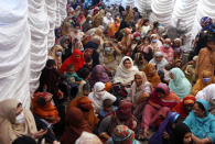 FILE - In this Saturday, April 10, 2021, file photo, women wait to receive food assistance for the upcoming Muslim fasting month of Ramadan, in Lahore, Pakistan. Muslims are facing their second Ramadan in the shadow of the pandemic. Many Muslim majority countries have been hit by an intense new coronavirus wave. While some countries imposed new Ramadan restrictions, concern is high that the month’s rituals could stoke a further surge. (AP Photo/K.M. Chaudary)