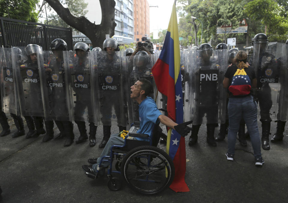 A demonstrator in a wheelchair rants at members of the Venezuelan National Police officers who temporarily blocked members of the opposition from getting to a rally against the government of President Nicolas Maduro in Caracas, Venezuela, Saturday, March 9, 2019. (AP Photo/Fernando Llano)