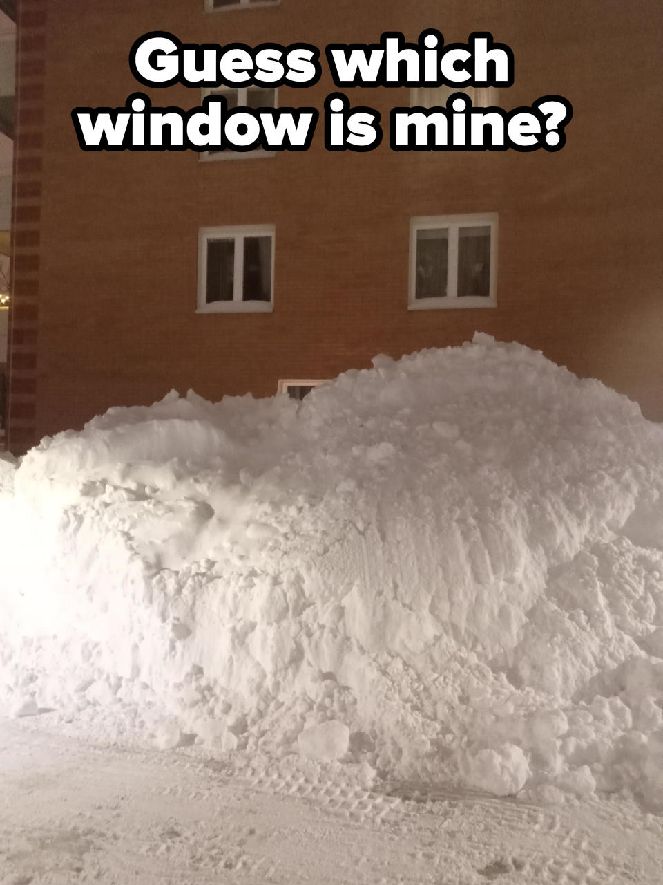 A mountain of snow covering the window of a building