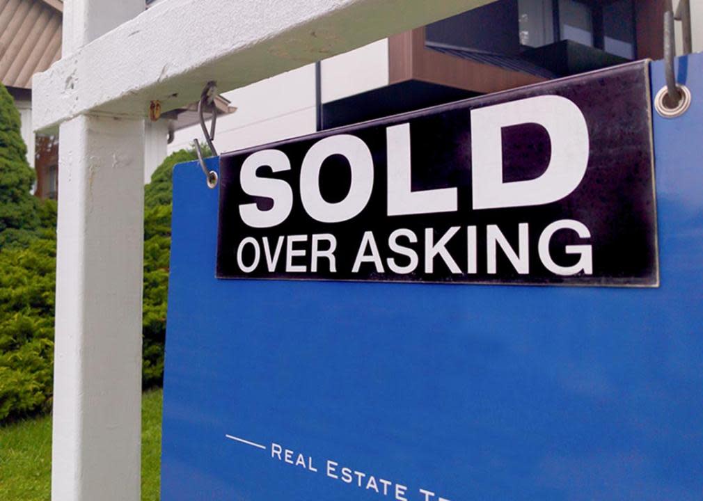 close up of "Sold over asking" sign in front of house