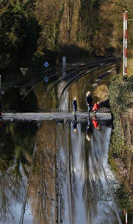 Residents are seen crossing the tracks after the river Thames flooded the railway in the village of Datchet, southern England February 10, 2014. REUTERS/Eddie Keogh