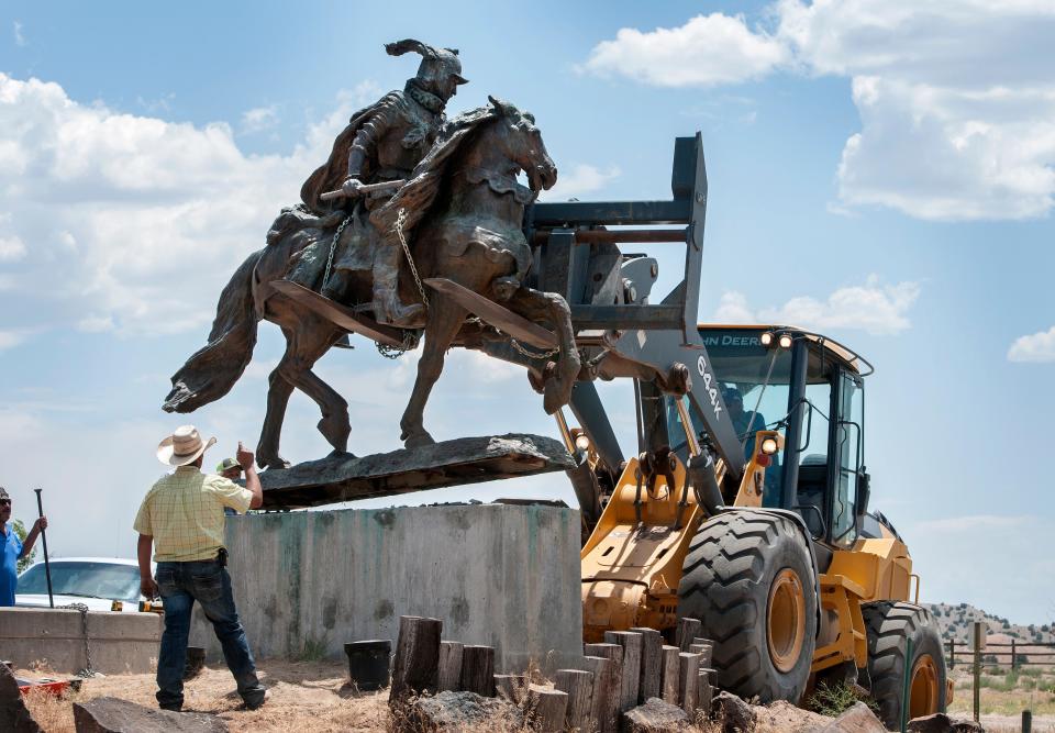 Rio Arriba County workers remove the bronze statue of Spanish conquerer Juan de Oñate from its pedestal in front of a cultural center in Alcalde, N.M., Monday, June 15, 2020. Crowds of people for and against the removal lined Highway 68 near of the center. (Eddie Moore/The Albuquerque Journal via AP)