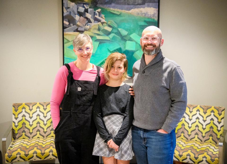 Kirin Clawson poses with her parents Beth Clawson, left, and Nathaniel Clawson, right, in their home Wednesday.