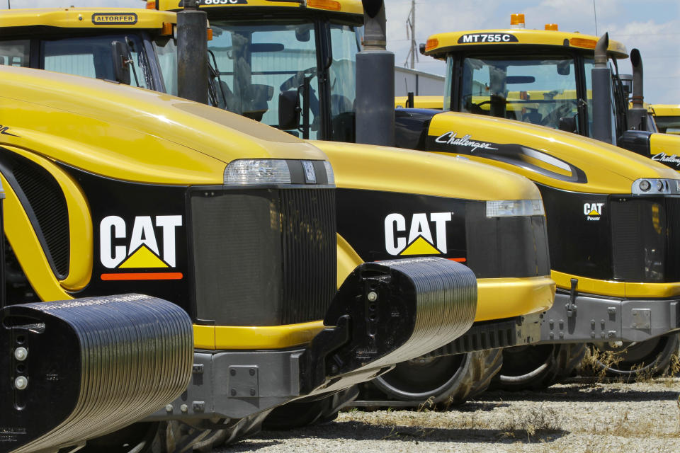 FILE - In this June 20, 2012 file photo, earth-moving tractors and equipment made by Peoria, Ill.-based Caterpillar Inc. are seen in Clinton, Ill.  Caterpillar and several mining companies have evacuated employees from Liberia. British Airlines has canceled flights to the region. Exxon and Chevron say they’re waiting to see whether public health authorities can contain the Ebola outbreak in three West African countries. (AP Photo/Seth Perlman, File)