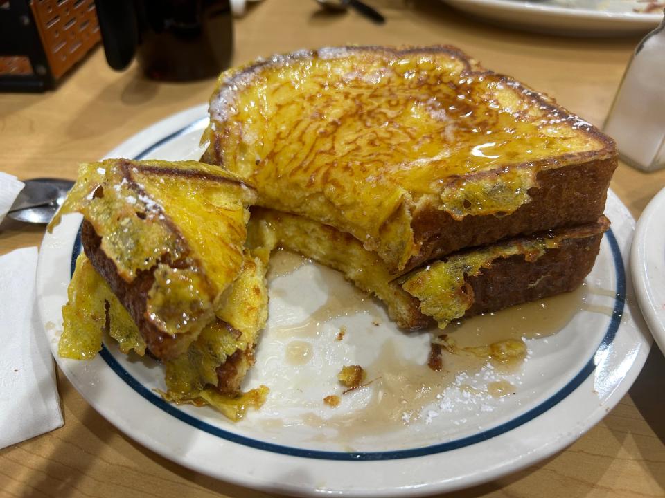 Slices of French toast with corners cut off on a plate. The French toast is covered in syrup