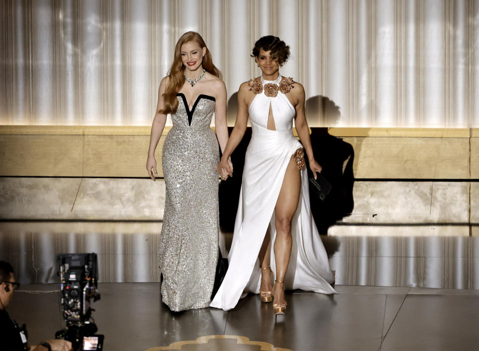 Jessica Chastain and Halle Berry walk onstage holding hands to present an award