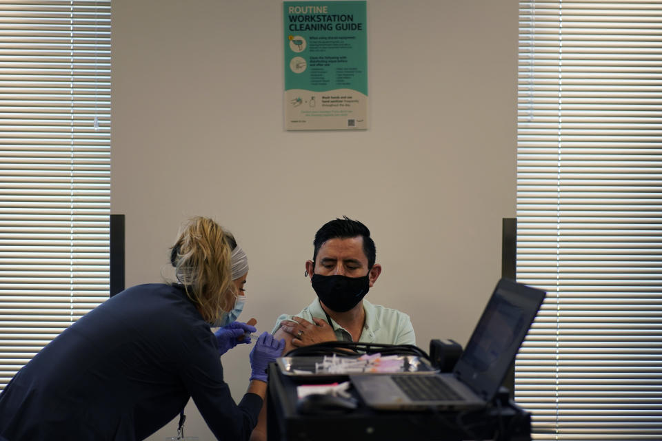 Amazon employee Juan Nunez gets a vaccination from registered nurse Deysi Felix at a vaccination event for workers at an Amazon Fulfillment Center, Wednesday, March 31, 2021, in North Las Vegas, Nev. A growing number of companies and labor unions are directly securing coronavirus vaccines for their workers. Amazon and some other large companies have hosted on-site inoculations, while smaller operations have helped book appointments for their workers. (AP Photo/John Locher)