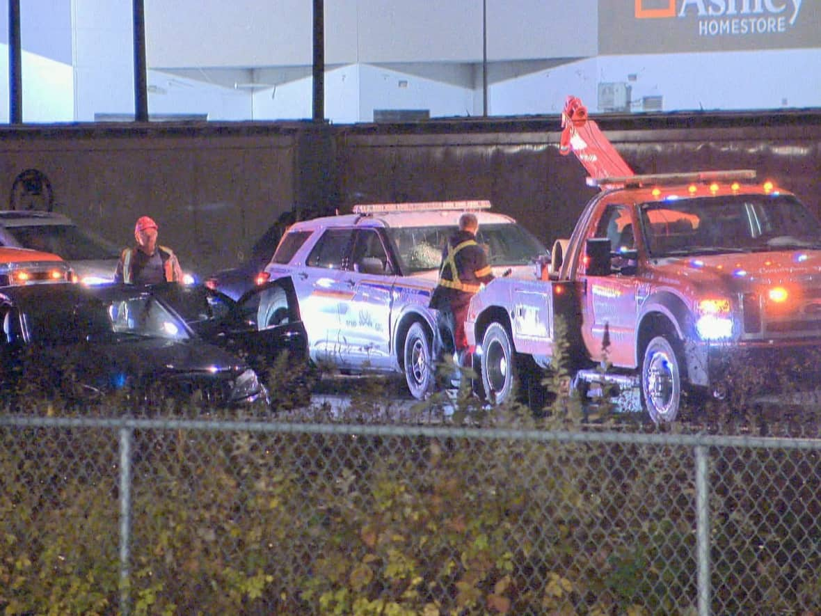 A tow truck and a police vehicle can be seen at one of multiple crime scenes after a robbery and police chase in Coquitlam, B.C., on Nov. 22, 2022. (Joel Law/CBC - image credit)