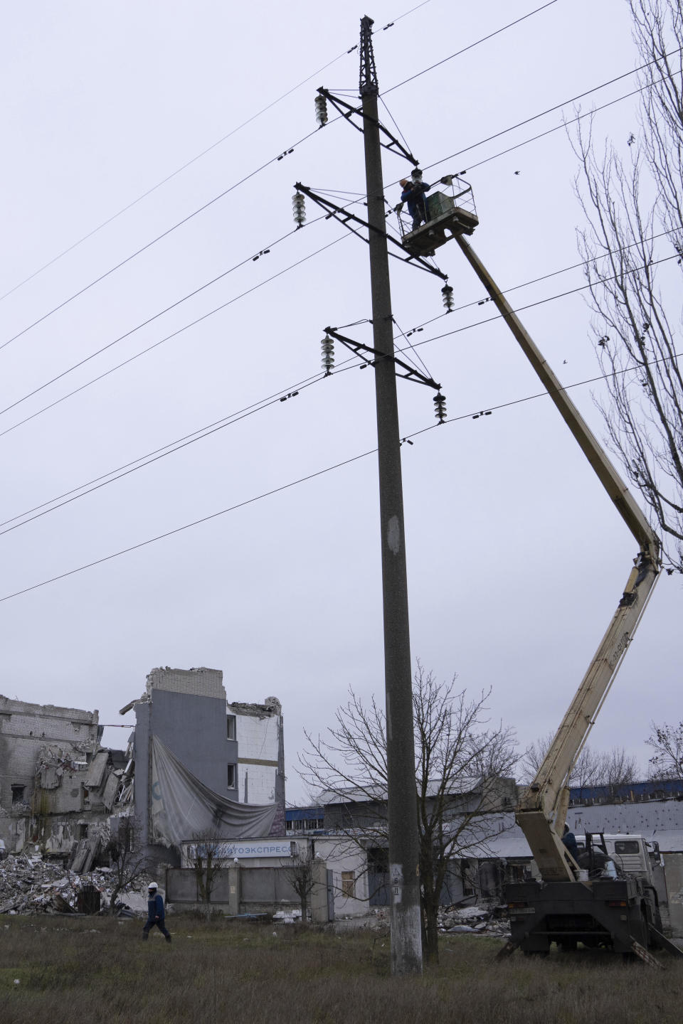 Workers repair electricity cables damaged during shelling by Russian forces in Kherson, Ukraine, December 3, 2022. / Credit: Evgeniy Maloletka/AP