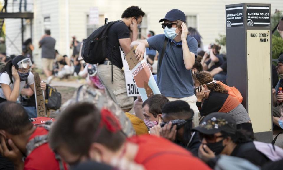 Demonstrators cover their ears as they expect police to deploy a long-range acoustic device on 3 July 2020, in Aurora, Colorado.