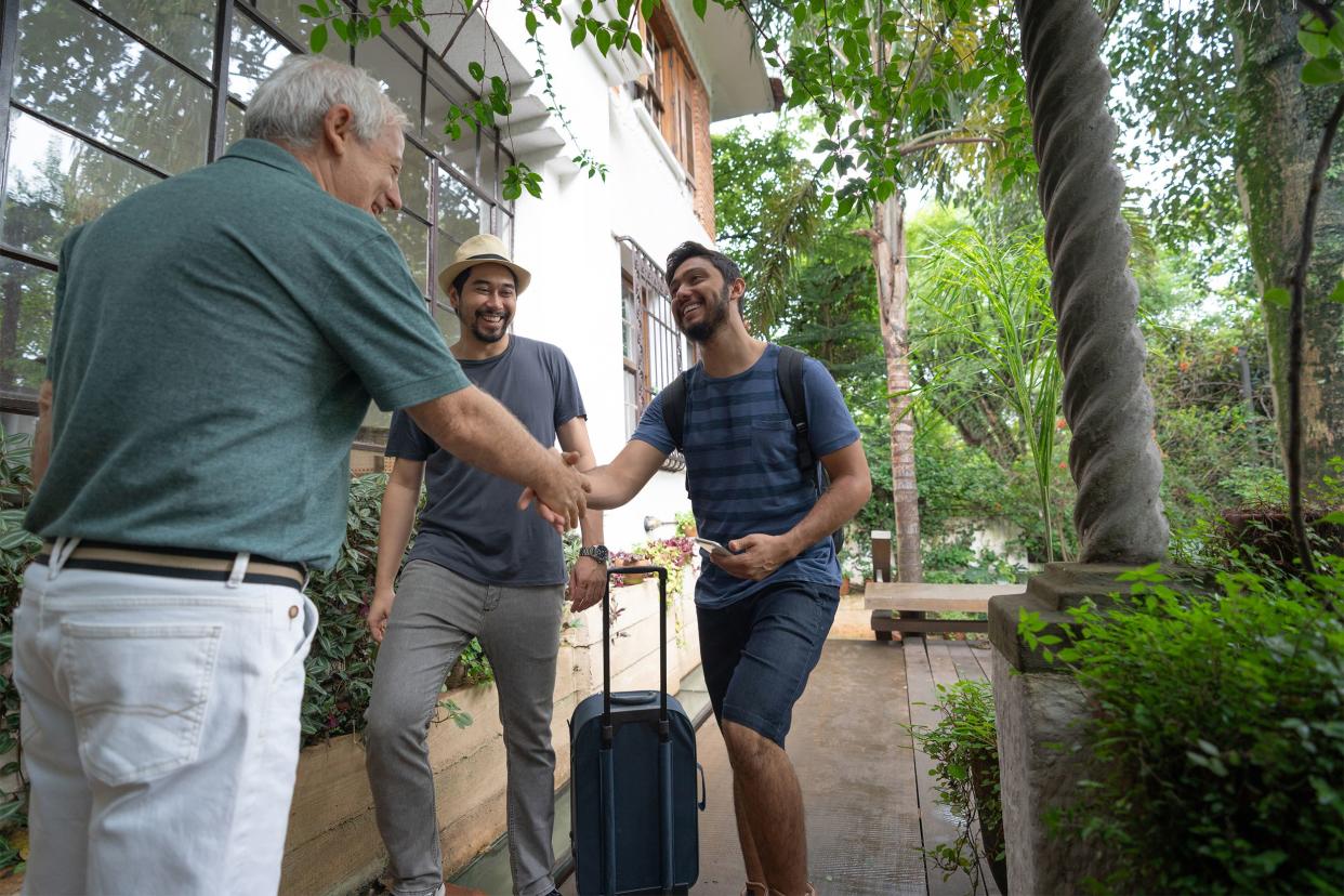 Senior man welcoming two younger men to rent his home