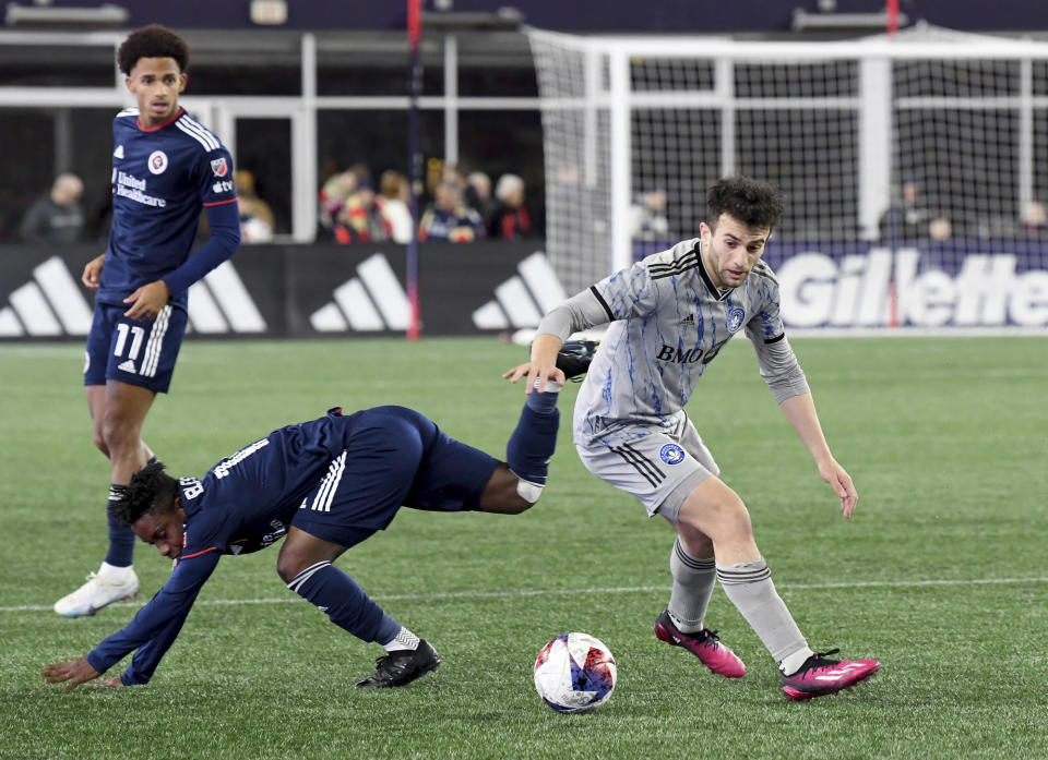 New England Revolution forward Latif Blessing, front left, falls to the ground as CF Montreal midfielder Ilias Iliadis, right, takes possession of the ball in the first half of an MLS soccer match Saturday, April 8, 2023, in Foxborough, Mass. (AP Photo/Mark Stockwell)