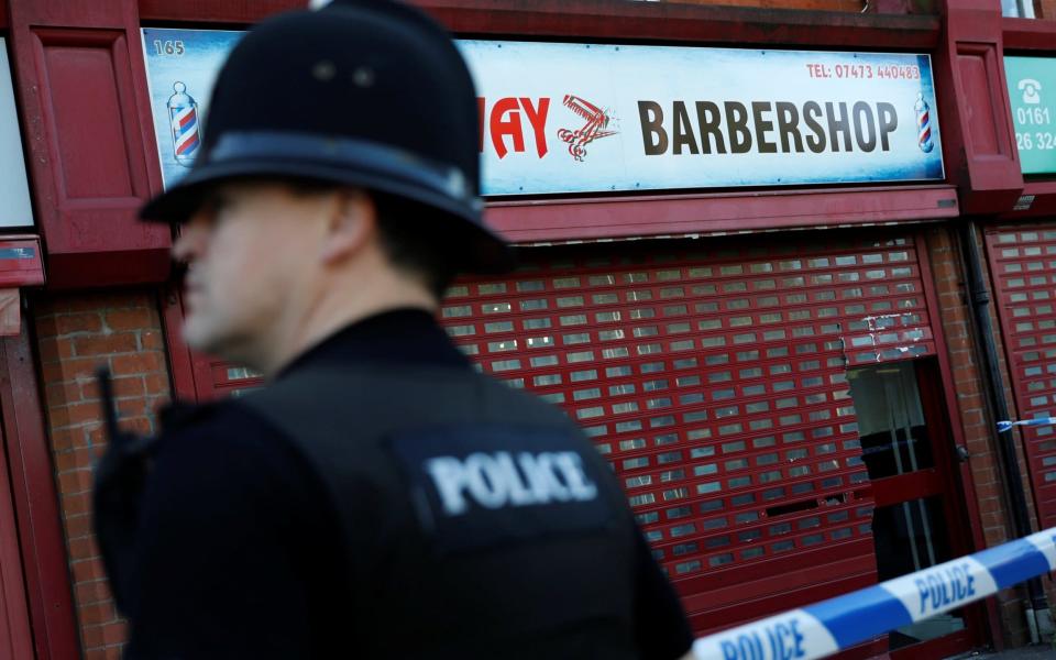 A police officer stands outside a barber's shop in Moss Side which was raided by officers in Manchester - Credit: DARREN STAPLES/Reuters