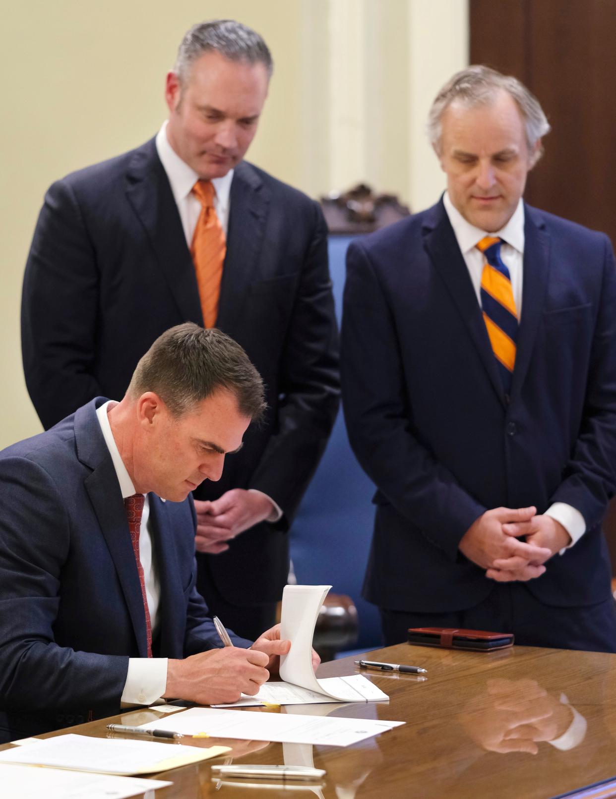 House Speaker Charles McCall and Senate President Pro Tem Greg Treat watch as Gov. Kevin Stitt signs legislation in 2021.