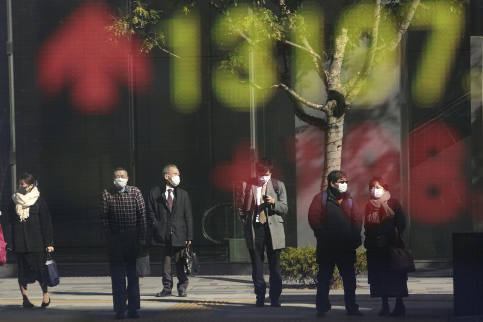 People are reflected on the electronic board of a securities firm in Tokyo, Wednesday, Jan. 20, 2021. Asian shares were mostly higher Wednesday, ahead of Joe Biden's inauguration as president, ending President Donald Trump’s four-year term. Japan's benchmark lost early gains as worries grew about the surge in coronavirus cases. (AP Photo/Koji Sasahara)