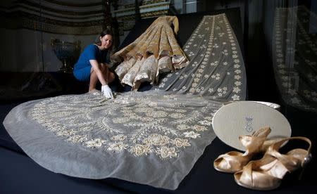 Curator Caroline de Guitar poses for photographers next to the wedding dress worn by Britain's Queen Elizabeth in 1947, ahead of the opening of an exhibition entitled 'Fashioning a Reign: 90 Years of Style from the Queen's Wardrobe', at Buckingham Palace, in London, Britain July 21, 2016. REUTERS/Peter Nicholls