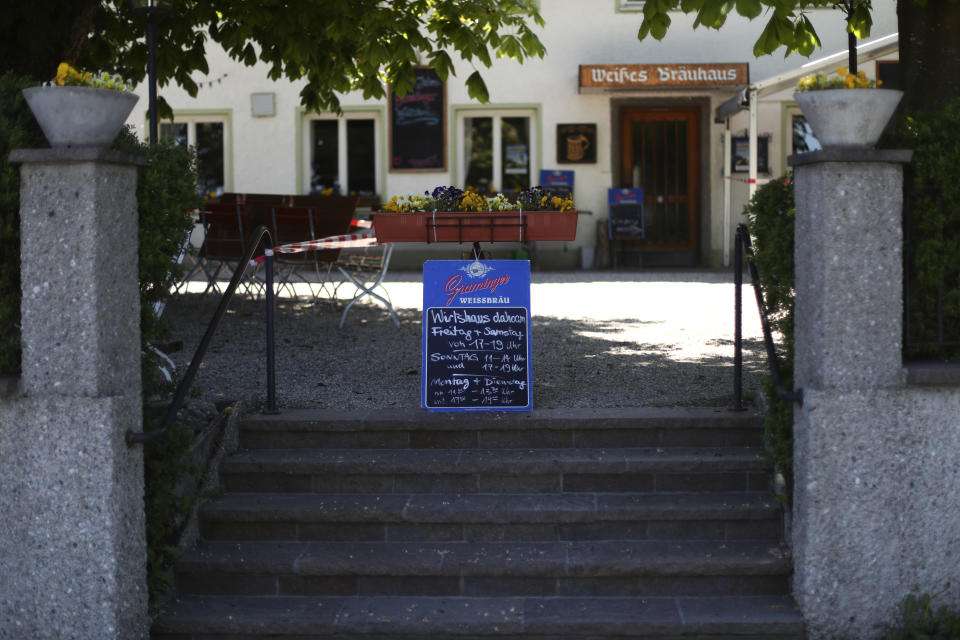 In this photo taken Thursday, May 7, 2020 an opening hours sign stand at the entrance of the beer garden of the120 year old family brewery and traditional Bavarian restaurant in Altoetting, Germany. The 'Graminger Weissbraeu' brewery, which has been in the same family for a century, is preparing to welcome guests back to its restaurant for the first time in two months — with new rules and fears for the future. (AP Photo/Matthias Schrader)