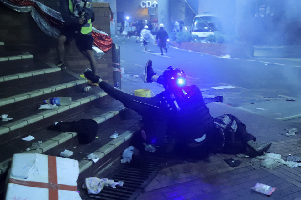 A policeman in riot gear detains a protester outside of Hong Kong Polytechnic University as police storm the campus in Hong Kong, early Monday, Nov. 18, 2019. Fiery explosions were seen early Monday as Hong Kong police stormed into a university held by protesters after an all-night standoff. (AP Photo/Kin Cheung)