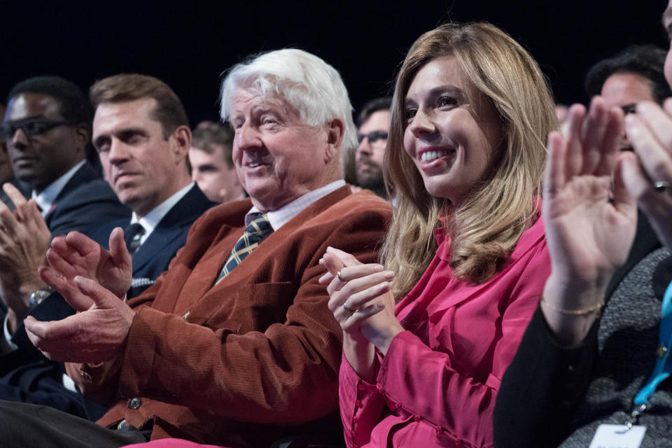 Carrie Symonds and Stanley Johnson, the partner and father of Prime Minister Boris Johnson, watch him deliver his speech during the Conservative Party Conference at the Manchester Convention Centre.