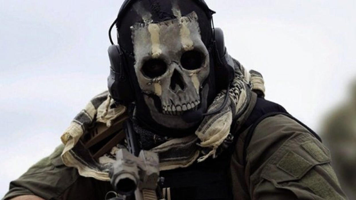  A soldier with a skeleton mask looks over their gun and into the camera 