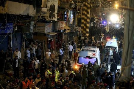 Red Cross vehicles drive by as residents and Lebanese army members inspect a damaged area caused by two explosions in Beirut's southern suburbs, Lebanon November 12, 2015. REUTERS/Khalil Hassan