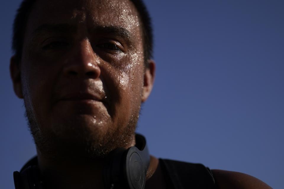 FILE - Sweat covers the face of Juan Carlos Biseno after dancing to music from his headphones as afternoon temperatures reach 115 degrees Fahrenheit (46.1 Celsius), July 19, 2023, in Calexico, Calif. A new study Tuesday, July 25, finds these intense and deadly hot spells gripping much of the globe in the American Southwest and Southern Europe could not have occurred without climate change. (AP Photo/Gregory Bull, File)