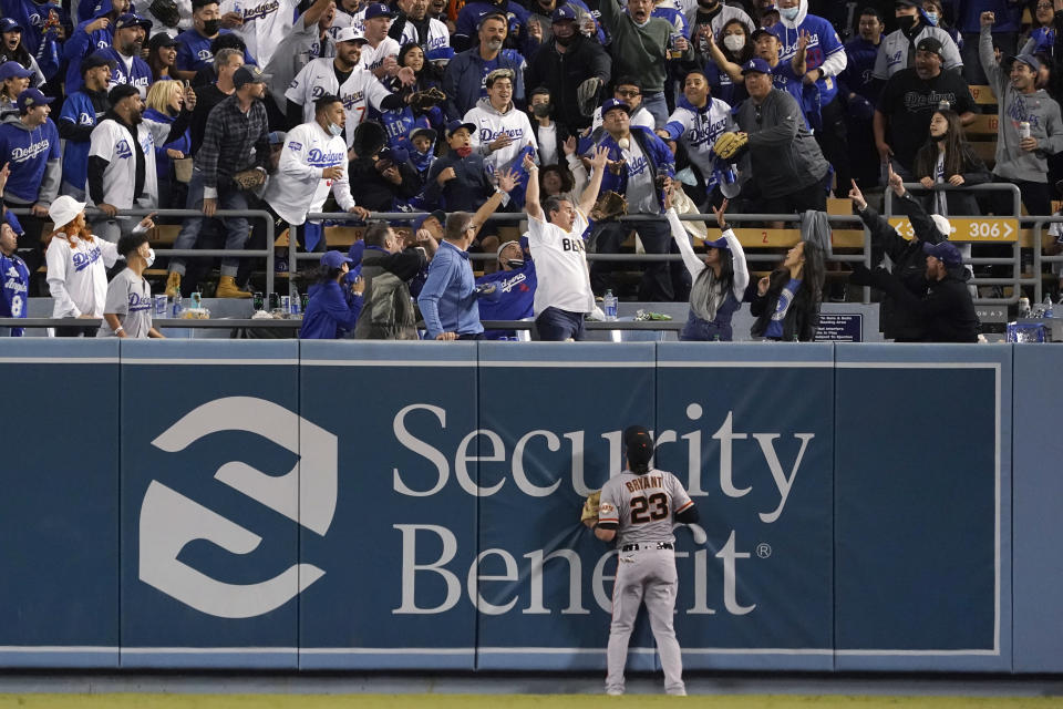 Fans at Dodger Stadium try to catch a two-run home run hit by Los Angeles Dodgers' Mookie Betts, as San Francisco Giants right fielder Kris Bryant (23) watches during the fourth inning of Game 4 of a baseball National League Division Series, Tuesday, Oct. 12, 2021, in Los Angeles. (AP Photo/Marcio Jose Sanchez)