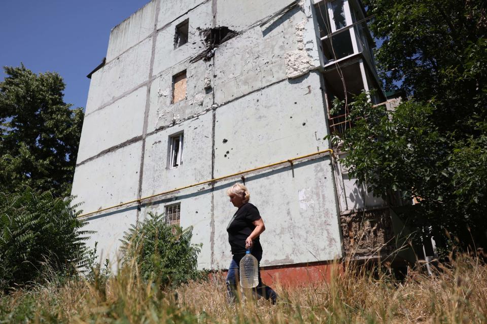 A local resident carries a container filled with drinking water from a fire engine supplied by Ukrainian rescuers in Hulyaypole, Zaporizhzhia Region (AFP via Getty Images)