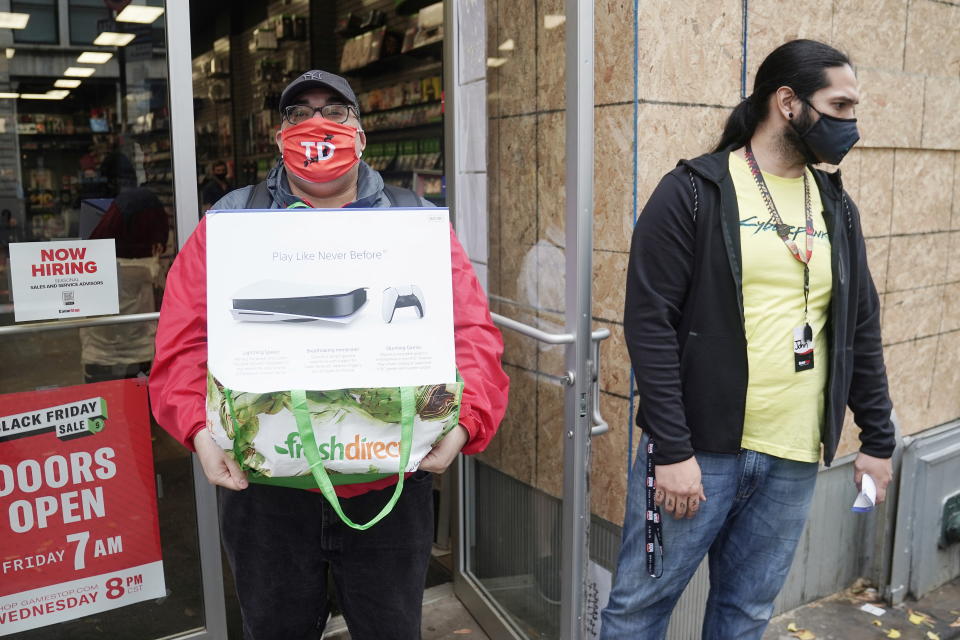 A man poses outside a GameStop store with his purchase of a Sony PS5 gaming console in the Manhattan borough of New York City, New York, U.S., November 12, 2020. REUTERS/Carlo Allegri