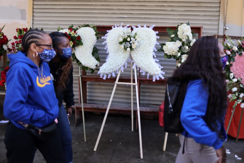 People walk past funeral flower displays in Los Angeles