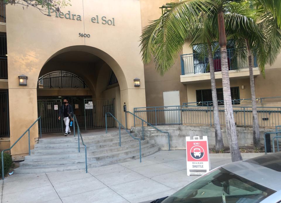 In this Sept. 17, 2020 photo, Miles Crawford, 22, leaves the Piedra del Sol campus apartments at San Diego State University in San Diego, Calif. A coronavirus outbreak of more than 700 cases reported at San Diego State University has put all of San Diego County, with more than 3 million people, at risk of having to close indoor dining and shopping, many for a third time under California guidelines. (AP Photo/Elliot Spagat)