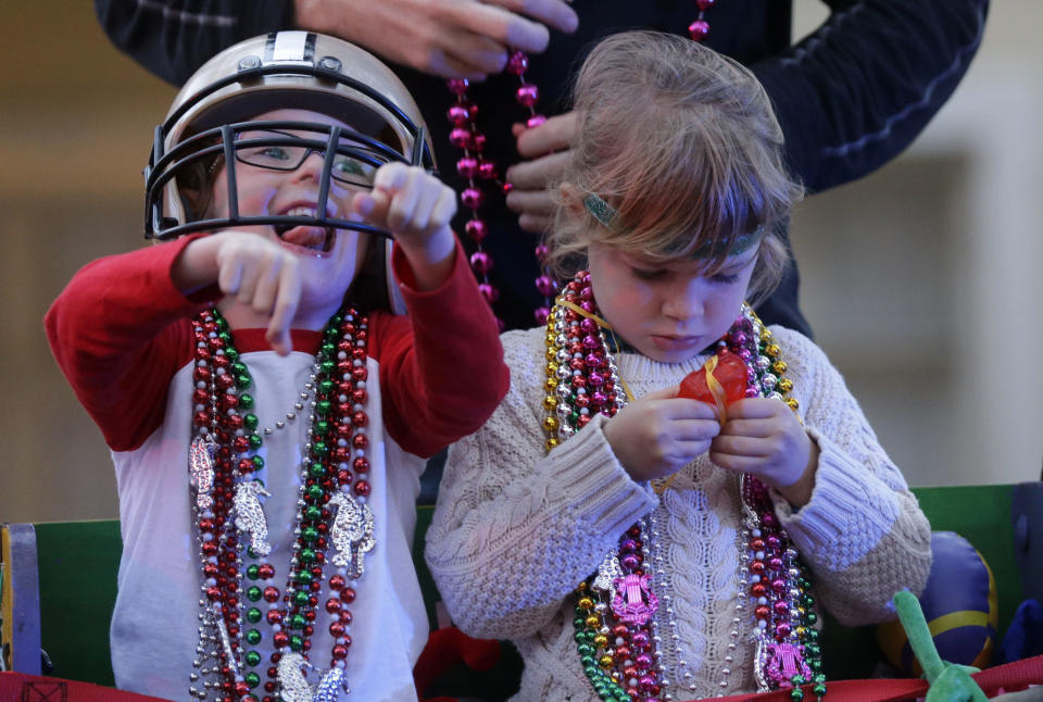 Barker Curry, 4, cheers to floats for beads and trinkets, while his cousin Sophia Curry, 3, right, looks at one of her trinkets, during the Krewe of Proteus Mardi Gras parade in New Orleans, Monday, Feb. 16, 2015. 