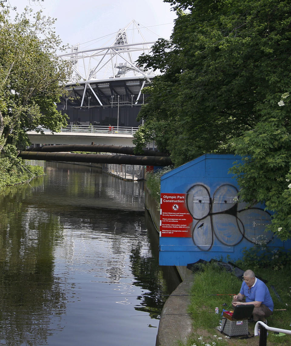 A fisherman sits alongside a cycle path near the Olympic Stadium on a canal in London, Thursday, May 24, 2012. There are many cycle paths across London that can be used to travel the capital. Like a runner or a swimmer, you would need to be physically fit. Like a goalie or a boxer, you should be prepared for close calls. But if you are coming to London's Summer Olympics _ and you have what it takes _ using a bicycle could be a great option in a city bracing for gridlock. (AP Photo/Kirsty Wigglesworth)