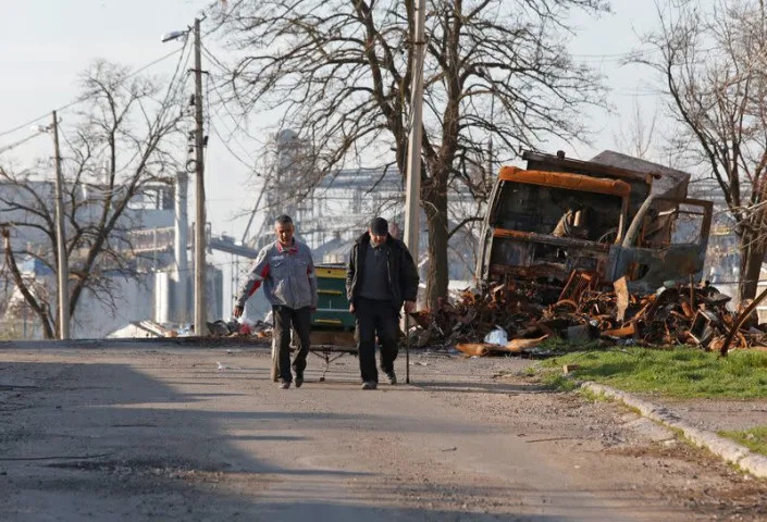 Cư dân địa phương đi ngang qua một chiếc xe bị phá hủy ở Mariupol