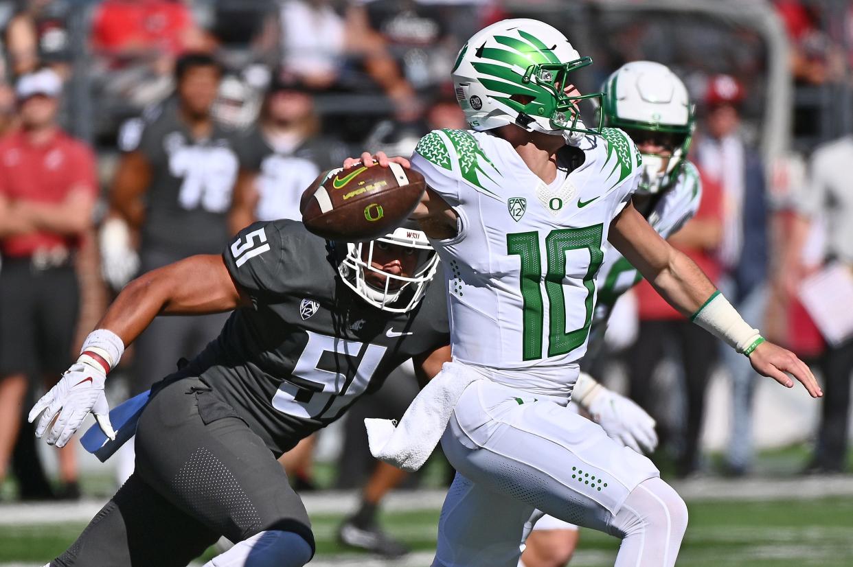 Oregon Ducks quarterback Bo Nix (10) is chased out of the pocket by Washington State Cougars linebacker Francisco Mauigoa (51) in the first half at Gesa Field at Martin Stadium Saturday.