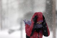 Srirupa Chatterjee holds her hood as she crosses a street Sunday, Jan. 5, 2014, in St. Louis. Heavy snow continues to fall Sunday with forecasters calling for up to a foot (30 centimeters) in eastern Missouri and parts of central Illinois followed by bitter cold. (AP Photo/Jeff Roberson)