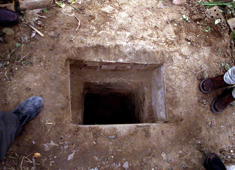 Journalists stand beside the spider hole in which Saddam Hussein was hiding when he was captured by U.S. troops on Saturday, during a media visit to the farm near Tikrit, December 15, 2003. Top members of Iraq's Governing Council said on Monday Saddam Hussein should be tried by Iraqis but that there should be some form of international involvement in the process. [Abdelaziz al-Hakim, president of the U.S.-appointed Council, cited the special tribunal set up by the Council last week as the proper court for a trial which many believe would lead to a death penalty.]