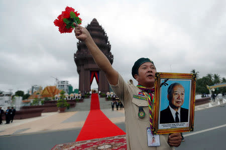 A Cambodian scout holds a picture of late king Norodom Sihanouk while attending the celebration marking the 64th anniversary of the country's independence from France, in Phnom Penh, Cambodia November 9, 2017. REUTERS/Samrang Pring